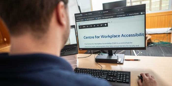 Employee looking at a computer monitor that reads "Centre for Workplace Accessibility"