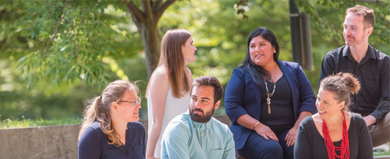 A group of six adult professionals sitting outdoors engaged in conversation