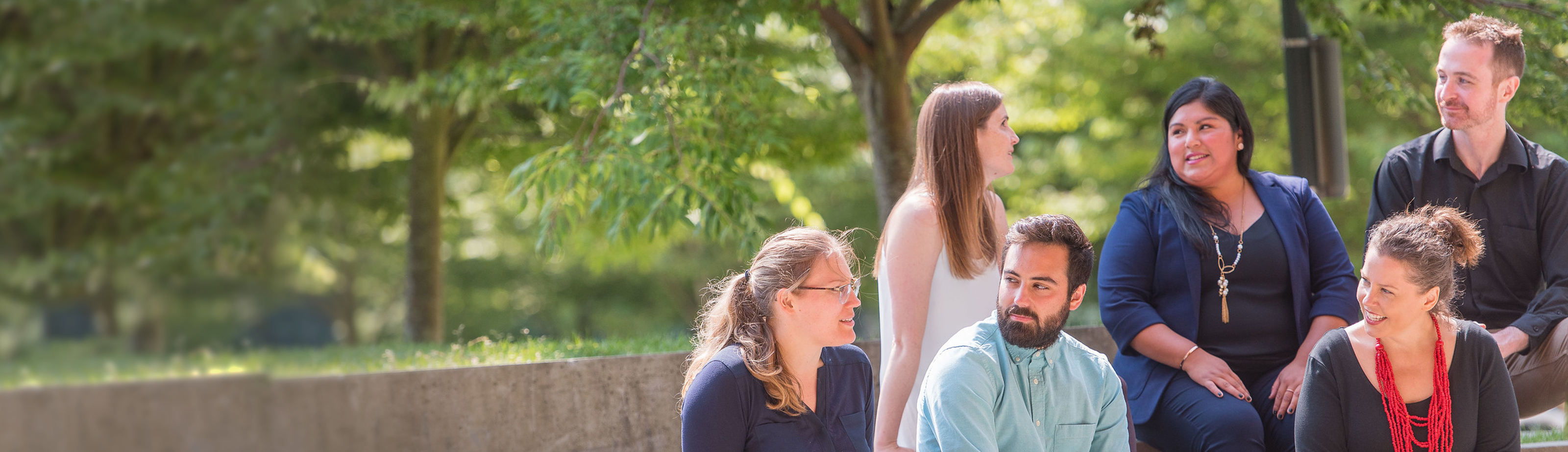 A group of six adult professionals sitting outdoors engaged in conversation