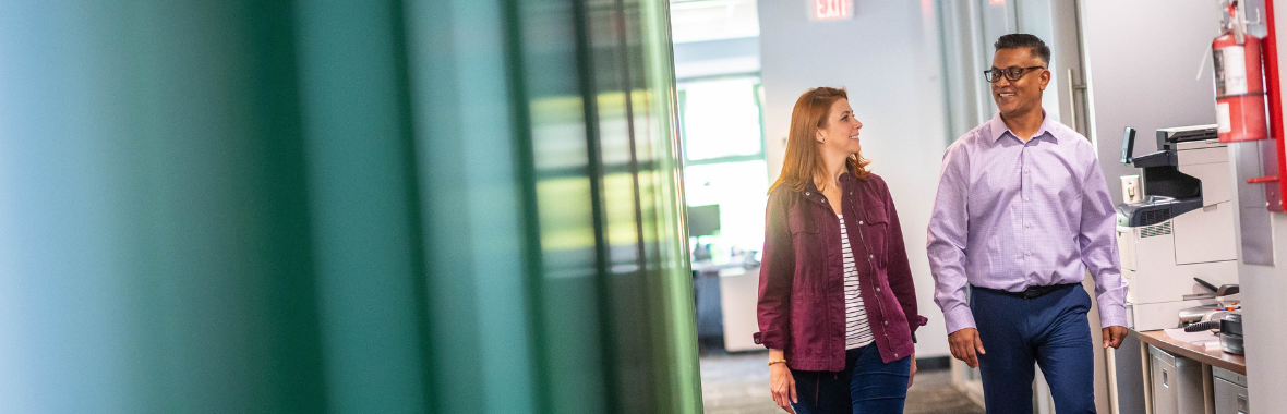 Two professionals walking side by side in an office space.