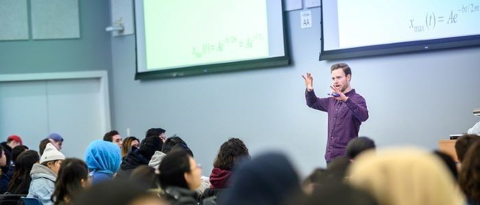 person teaching in front of students in a lecture hall