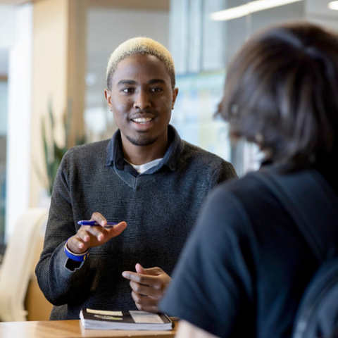 Individual talking to someone behind a counter and smiling.
