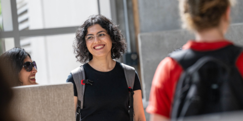 Person walking around outside wearing backpack and smiling