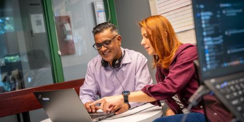 Two people looking at a laptop, smiling 