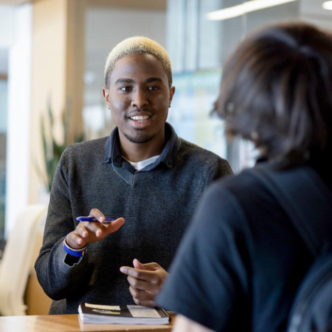 Individual standing at desk talking to someone