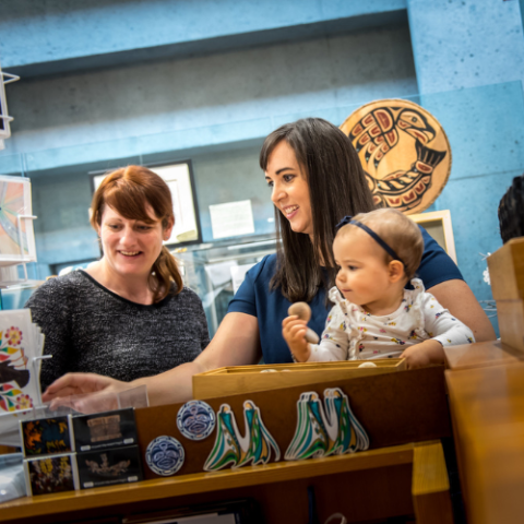 Two women with a baby at the Museum of Anthropology giftshop.