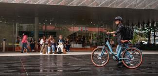 Young man wearing a helmet standing beside blue e-bike outdoors