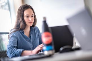 professional woman sitting indoors working on laptop