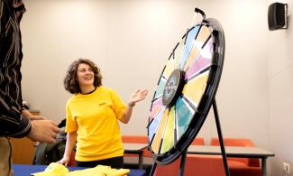 Individual in yellow Thrive shirts spins a wheel to win prizes