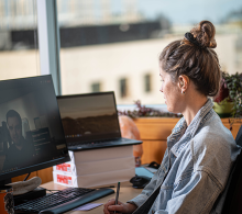 Young professional wearing assistive hearing device sitting and working on a computer.