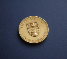 Golden coin with UBC crest embossed on it.