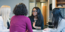 three people sitting at a table talking about wellbeing. 