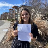 Rachel Hussey standing at UBC Okanagan, smiling, holding a piece of paper