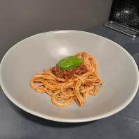 A plate of spaghetti with a green basil leaf for garnish